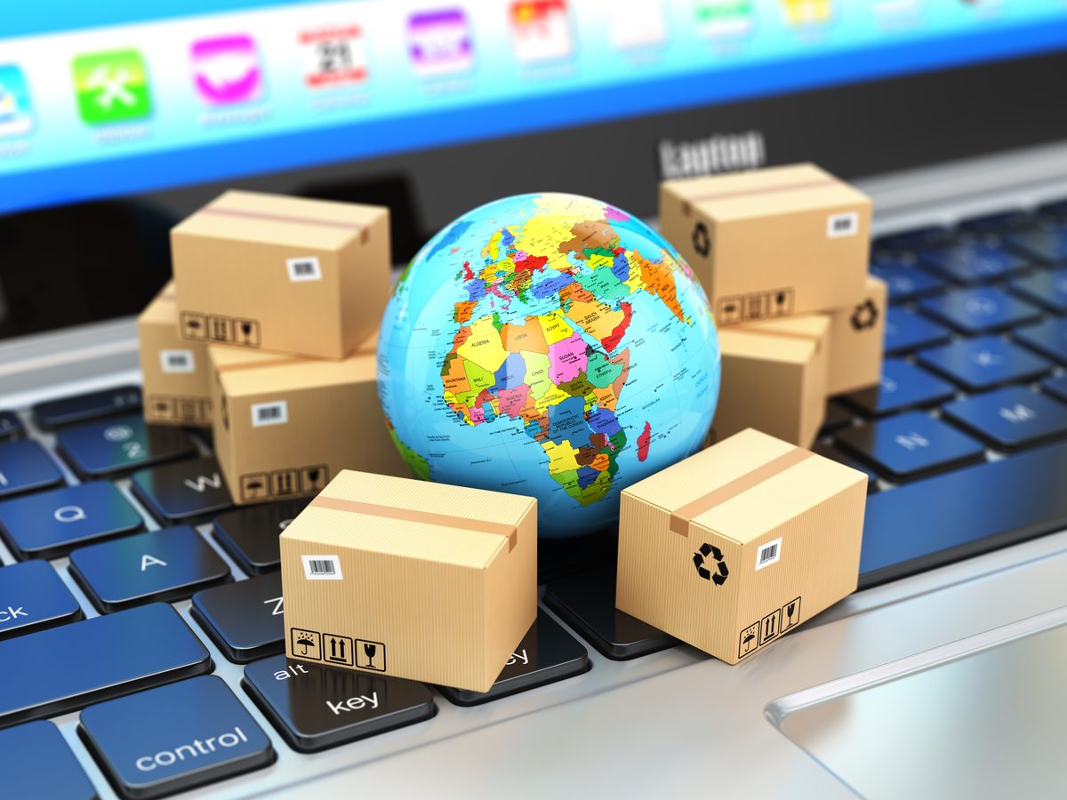 Parcels and a globe on a laptop keyboard, representing systems and logistics delivery